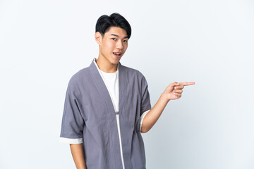 Young Chinese man isolated on white background pointing finger to the side and presenting a product