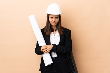 Young architect woman holding blueprints over isolated background with unhappy expression
