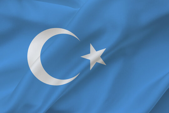 East Turkistan flag on waving silk background. Uyghur Turkish flag. Fabric texture.