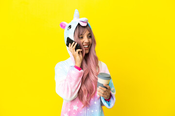 Young mixed race woman wearing a unicorn pajama isolated on white background holding coffee to take...
