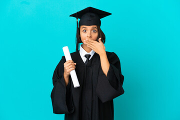 Young university graduate girl over isolated blue background covering mouth with hands