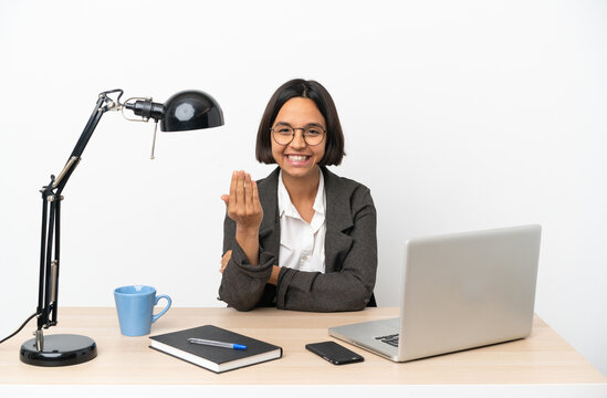 Young business mixed race woman working at office inviting to come with hand. Happy that you came