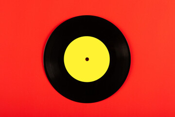 Black vinyl record with yellow label on red background.Top view.