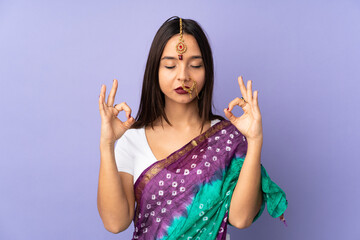 Fototapeta na wymiar Young Indian woman isolated on purple background in zen pose