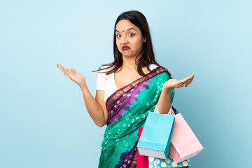 Young Indian woman with shopping bags making doubts gesture