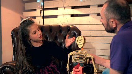 Inquisitive daughter asking her father many questions about human body structure. They are happy to...