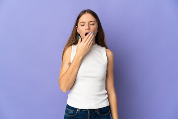 Young Lithuanian woman isolated on purple background yawning and covering wide open mouth with hand