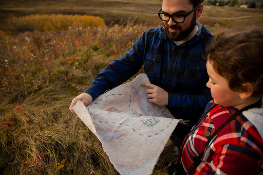 Father and son with treasure map in field