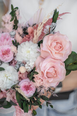 A beautiful summer bouquet in the hands of a girl. Bouquet of spray roses, peonies and French roses in white-pink tones.