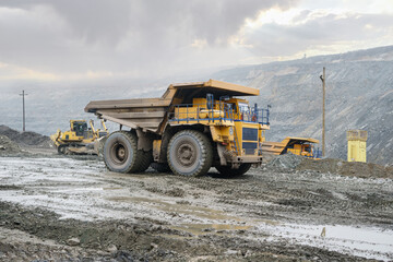 A large open-pit dump truck rides in an open-pit ore quarry. Part of the technological process of open-pit mining.