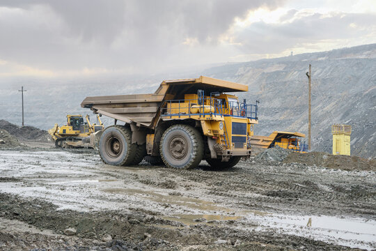 A large open-pit dump truck rides in an open-pit ore quarry. Part of the technological process of open-pit mining.