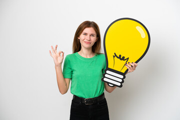 Young English woman isolated on white background holding a bulb icon and doing OK sign