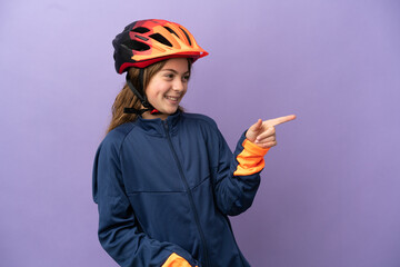 Little caucasian girl isolated on purple background pointing finger to the side and presenting a product