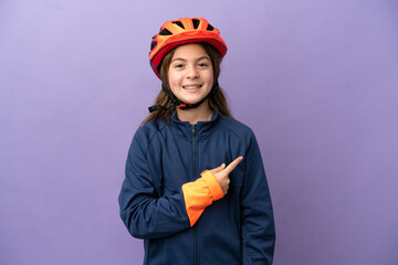 Little caucasian girl isolated on purple background pointing to the side to present a product
