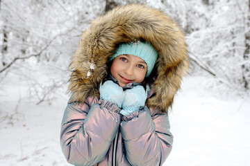 Fototapeta na wymiar A girl in warm winter overalls on a walk in the winter forest: active games, playing snowballs and other activities