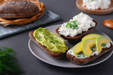 Sandwiches with a minced curd, avocado and herbs on the natural wooden cutting board. Healthy food concept