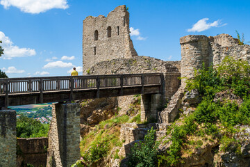 Ruins of Castle Neumarkt Germany Castle Wolfstein  with blue sky and person standing on bridge and jagged rocks - obrazy, fototapety, plakaty