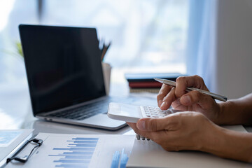 Close-up calculator  to calculate the company's financial results On the wooden table in the office and business work background, tax, accounting, statistics, and analytical research concept