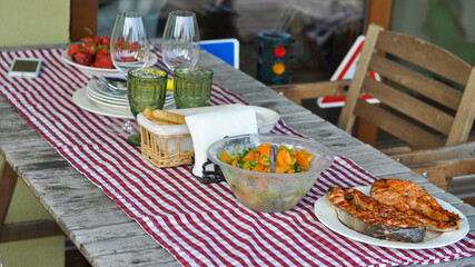 serving table with grilled fish, vegetable salad and vegetables on plates. selective focus macro shot with shallow DOF
