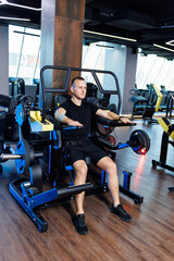 Fototapeta na wymiar Attractive adult man doing exercises and lifting weights in the gym. Sports training in the gym
