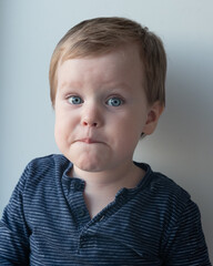 portrait of a little boy with blue eyes in a blue blouse on a white background smiling