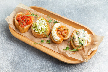 Assorted bruschettes on a wooden plate.