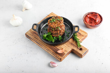 Frying pan with tasty lentil cutlets on light background