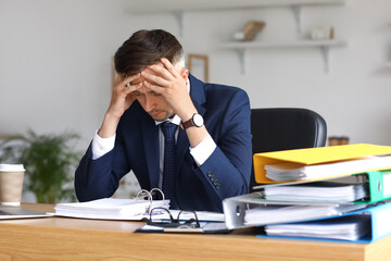 Tired businessman working with documents in office