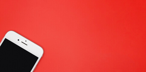 Red background with croped phone and copy space. Top view.