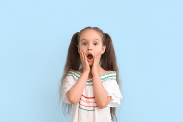 Portrait of shocked little girl with ponytails on blue background