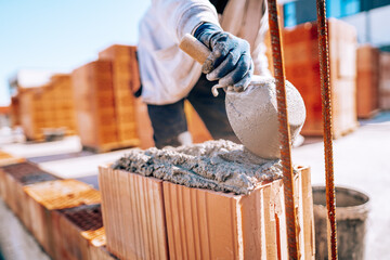 Bricklayer industrial worker installing brick masonry on exterior wall with trowel putty knife