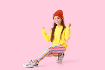 Adorable little girl in yellow hoodie dancing on pink background