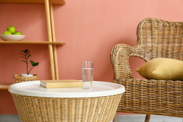Glass of water and book on rattan table in living room
