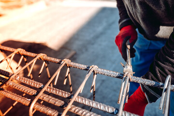 people details of construction worker hands securing steel bars with wire rod for reinforcement of...