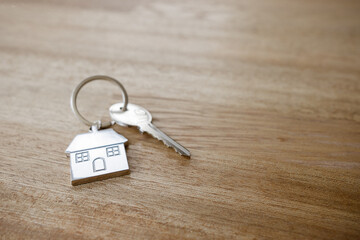 One silver key with a silver key chain in the shape of a house real estate investment