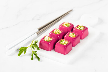 Beetroot cream jelly in the form of small portions of a square shape with a filling of finely chopped egg with parsley on a serving board on a white background