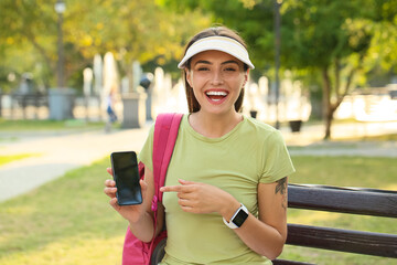Young female tourist with mobile phone in park