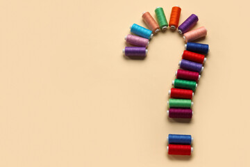 Question mark made of sewing threads on beige background