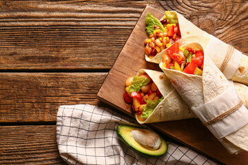 Board of tasty Mexican burritos with vegetables on wooden background,, closeup