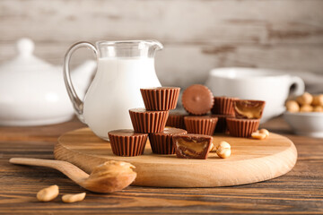 Board with tasty chocolate candies with peanut butter on wooden background