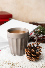 Cup of tasty coffee, blank book and Christmas decor on light background