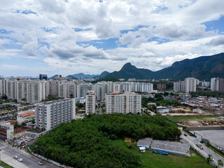 Aerial view of the Coronel Pedro Correia road and its surroundings, in Jacarépagua, Rio de Janeiro, Brazil. Residential buildings and mountains in the background. Cloudy day. Drone photo