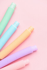 Different colorful Pop Tubes on pink background