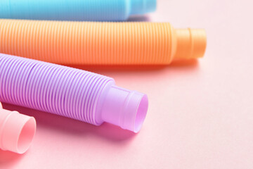 Different colorful Pop Tubes on pink background, closeup