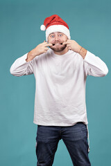 a young man in a Santa hat, making a face, stretches his mouth