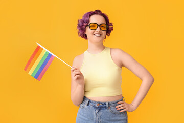 Young woman with LGBT flag on yellow background