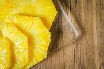 Young Woman cutting a pineapple on a wooden table in the kitchen