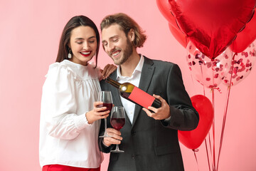 Happy young couple with balloons and wine on color background. Valentine's Day celebration