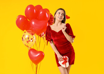 Beautiful young woman with gift and balloons on color background. Valentine's Day celebration