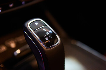 Automatic gear stick of a modern car, multimedia and navigation control buttons. Car interior details. Transmission shift. Shallow dof